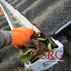 orange gloved hand cleaning leaves from rain gutter